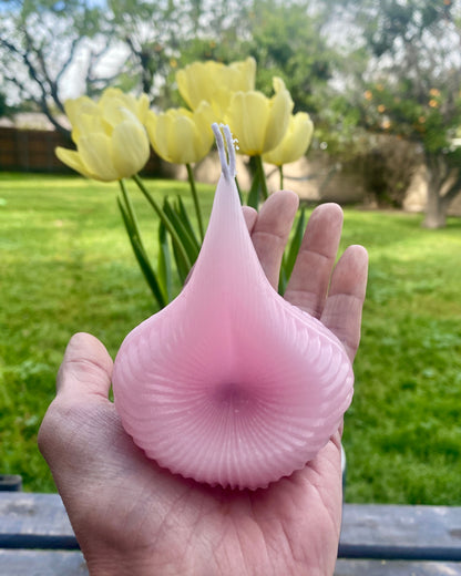 A hand holding up a pink Destiny Decision Candle outdoors with yellow tulips in the background.  Showing the true size of the Destiny Decision Candle.